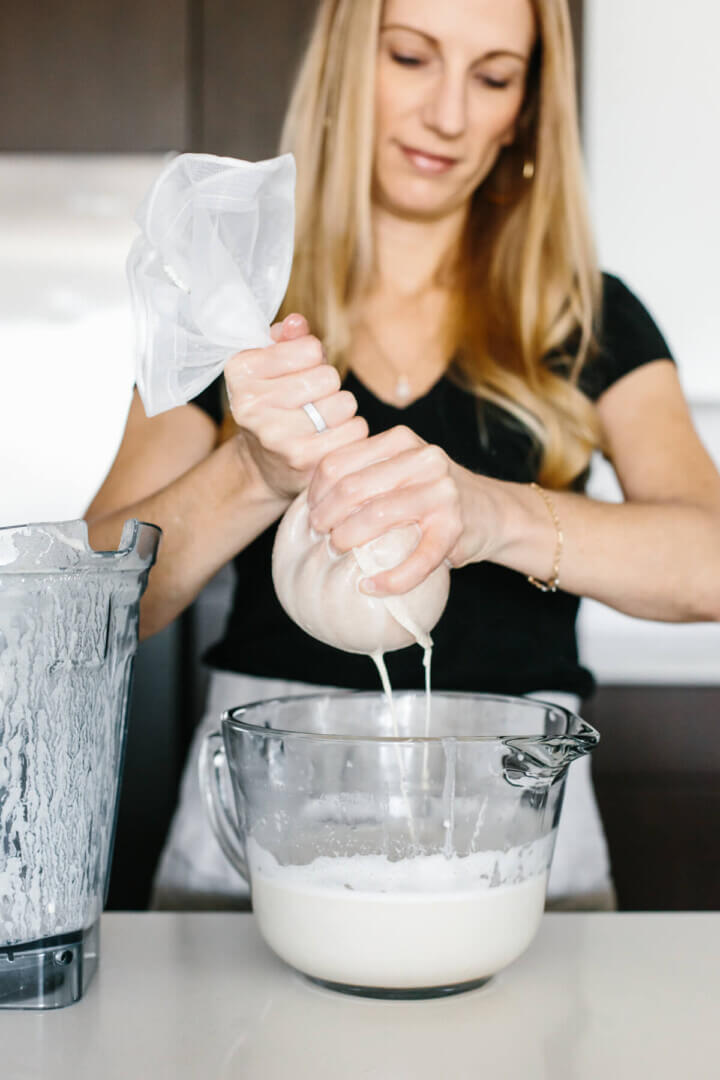 Squeezing almond milk through a nut milk bag