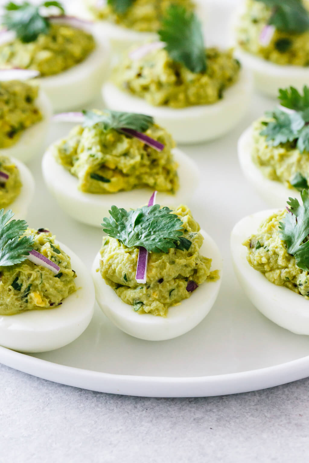 Several avocado deviled eggs on a white plate.