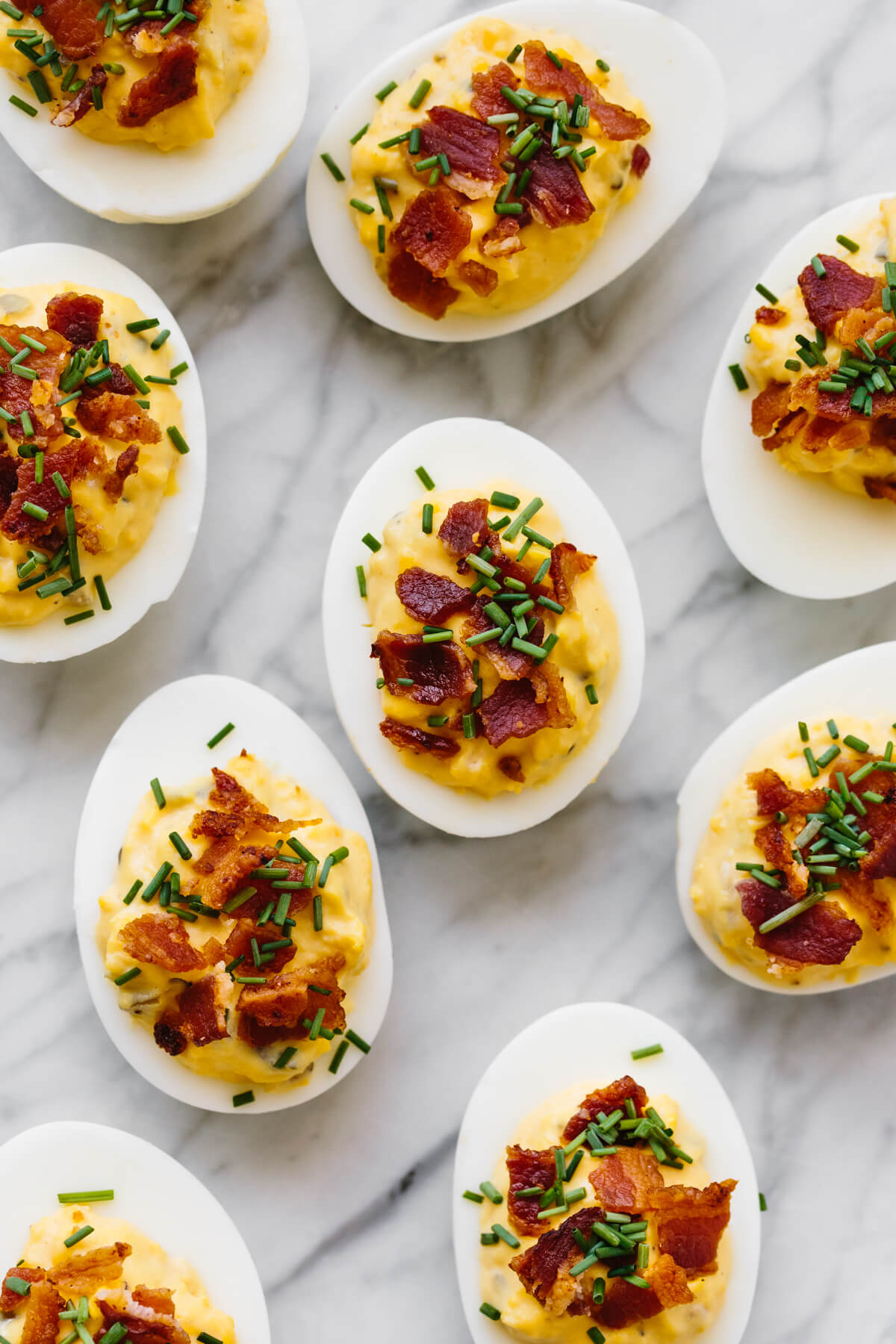 Several bacon deviled eggs on a marble counter.