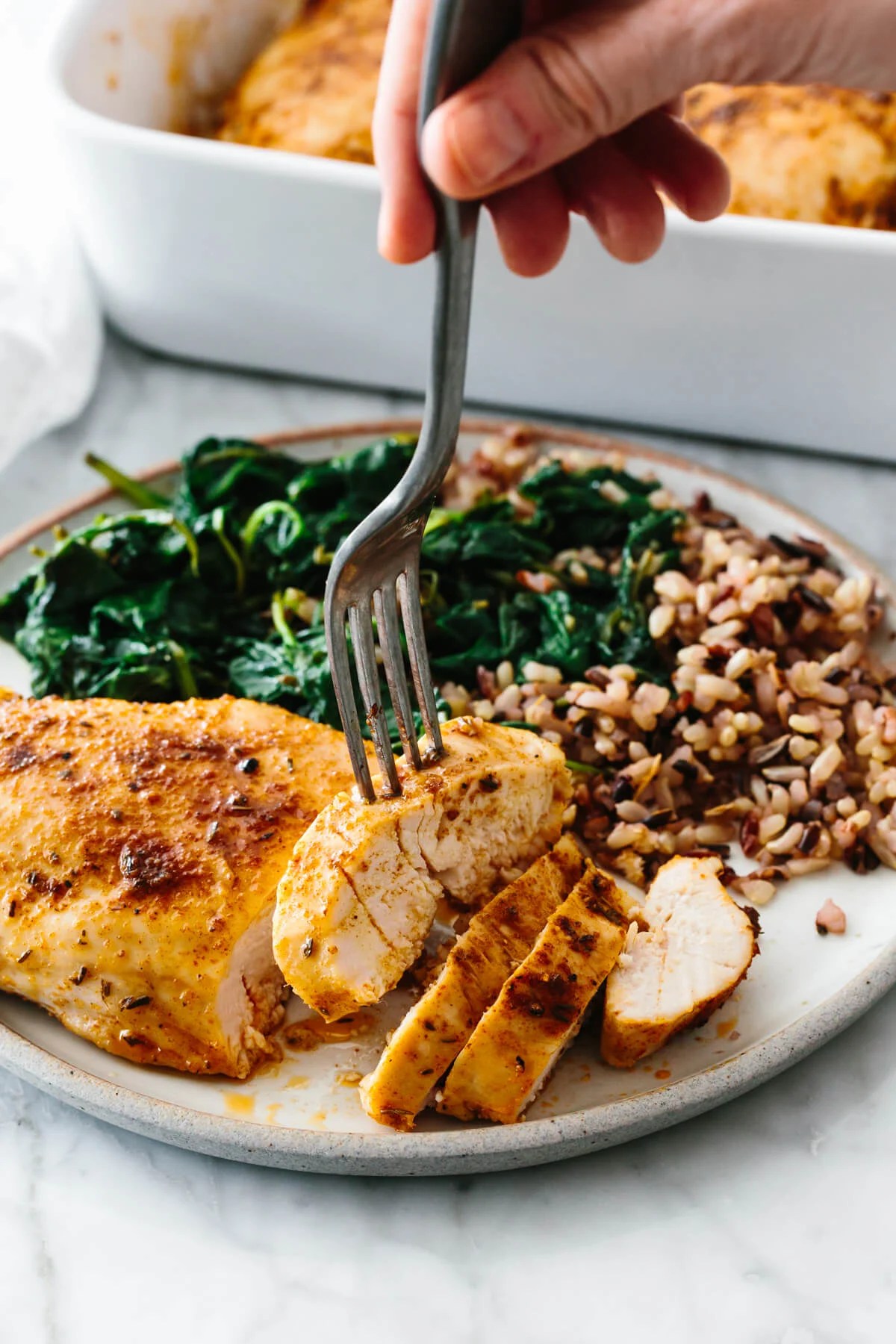 Baked chicken breast with spinach and rice on a plate.