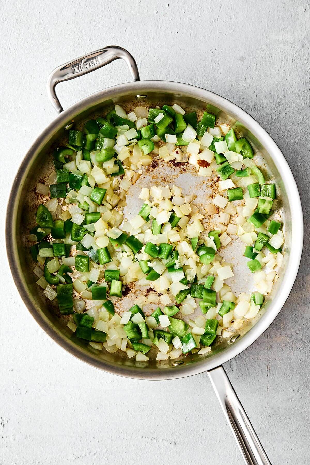 Cooked onion and peppers in a pan.