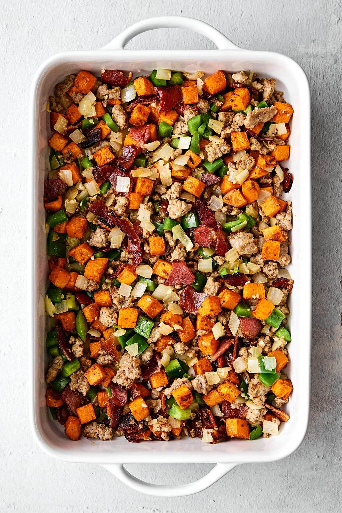 Prepping a breakfast casserole in a baking dish.