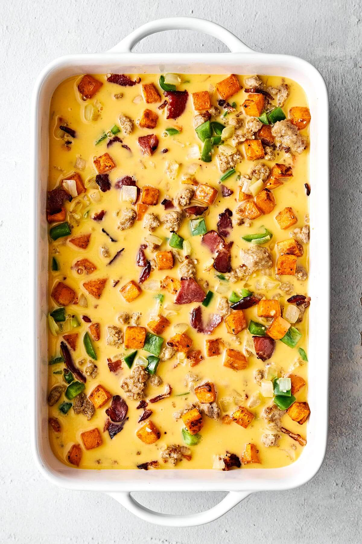 Eggs, meats, and veggies in a baking dish.