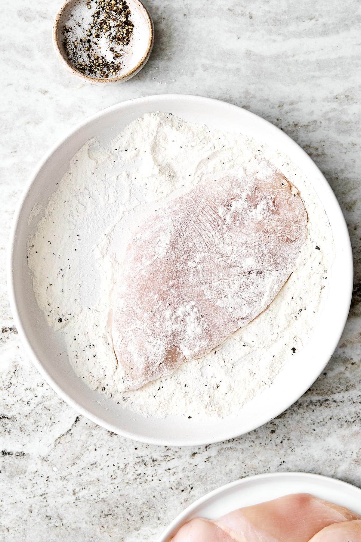 Dredging chicken in flour.