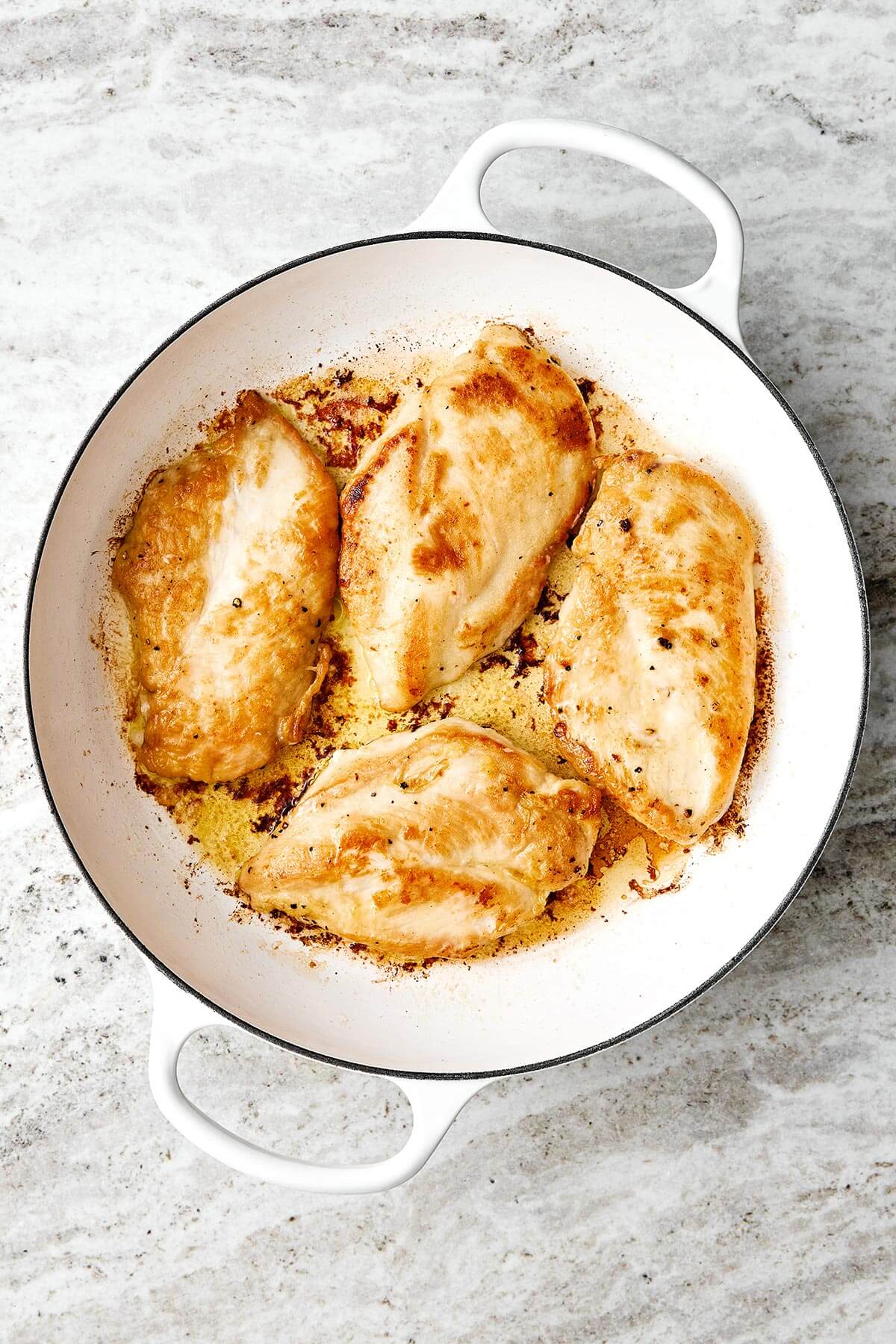 Searing chicken breasts in a pan.