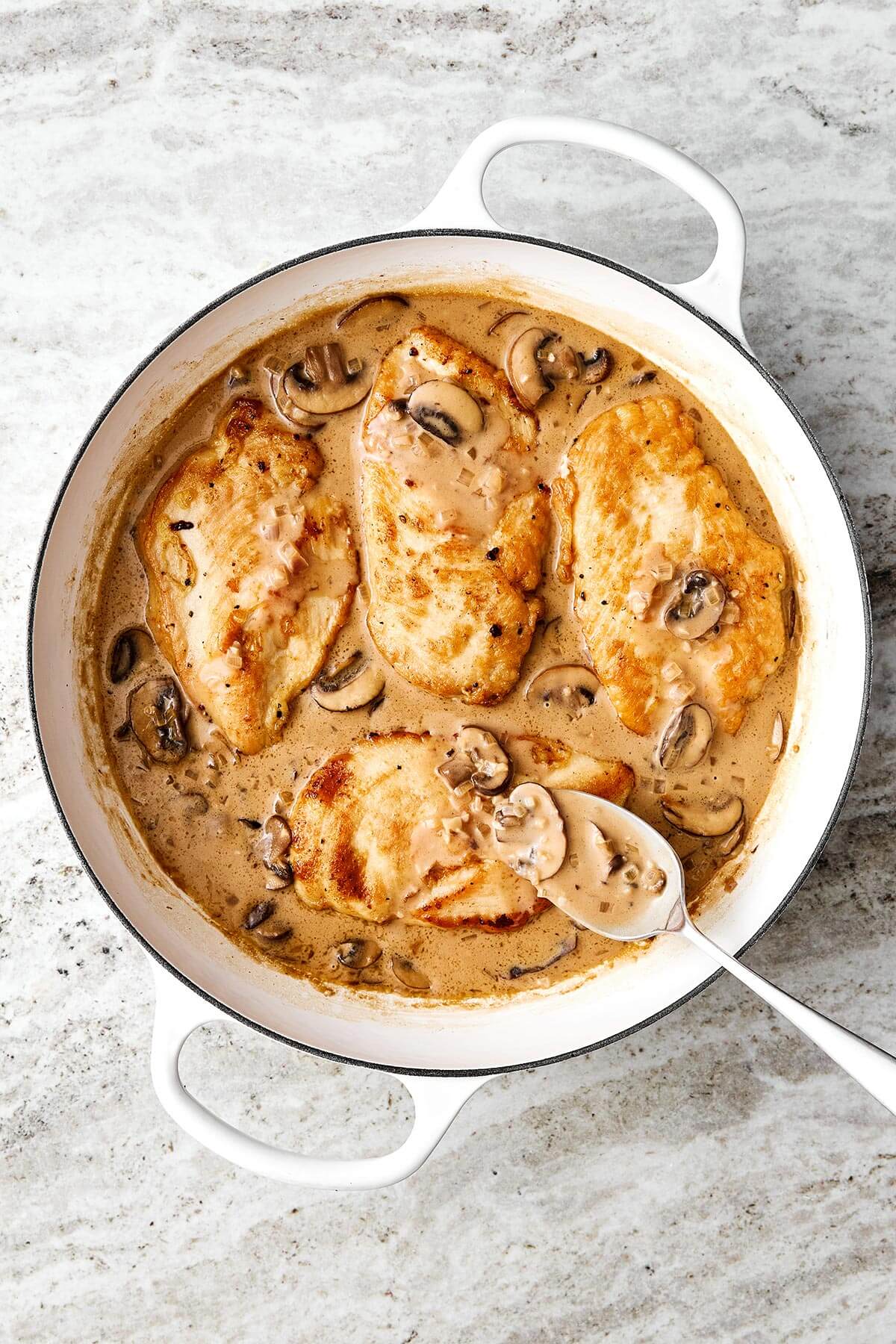 Cooking chicken Marsala in a pan.