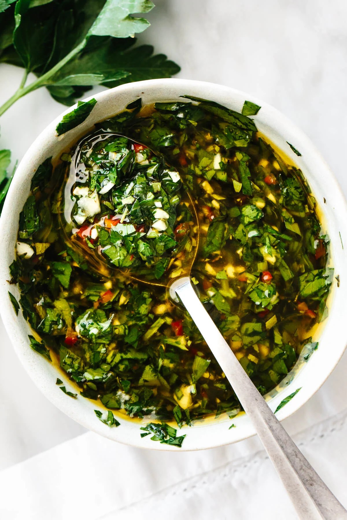 A bowl of chimichurri sauce with a spoon