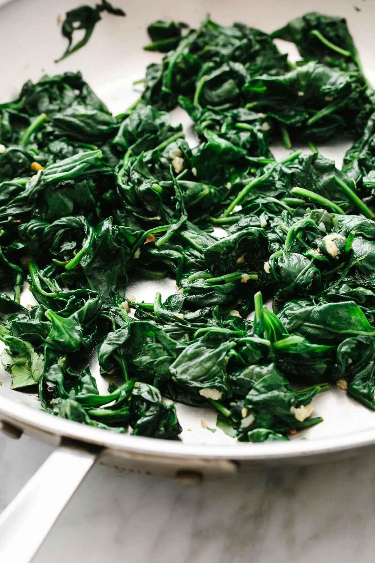 A pan with garlic sauteed spinach on a table.