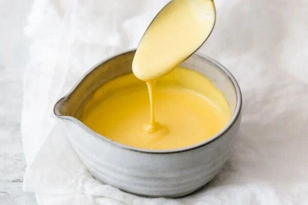 Hollandaise sauce dripping off a spoon.