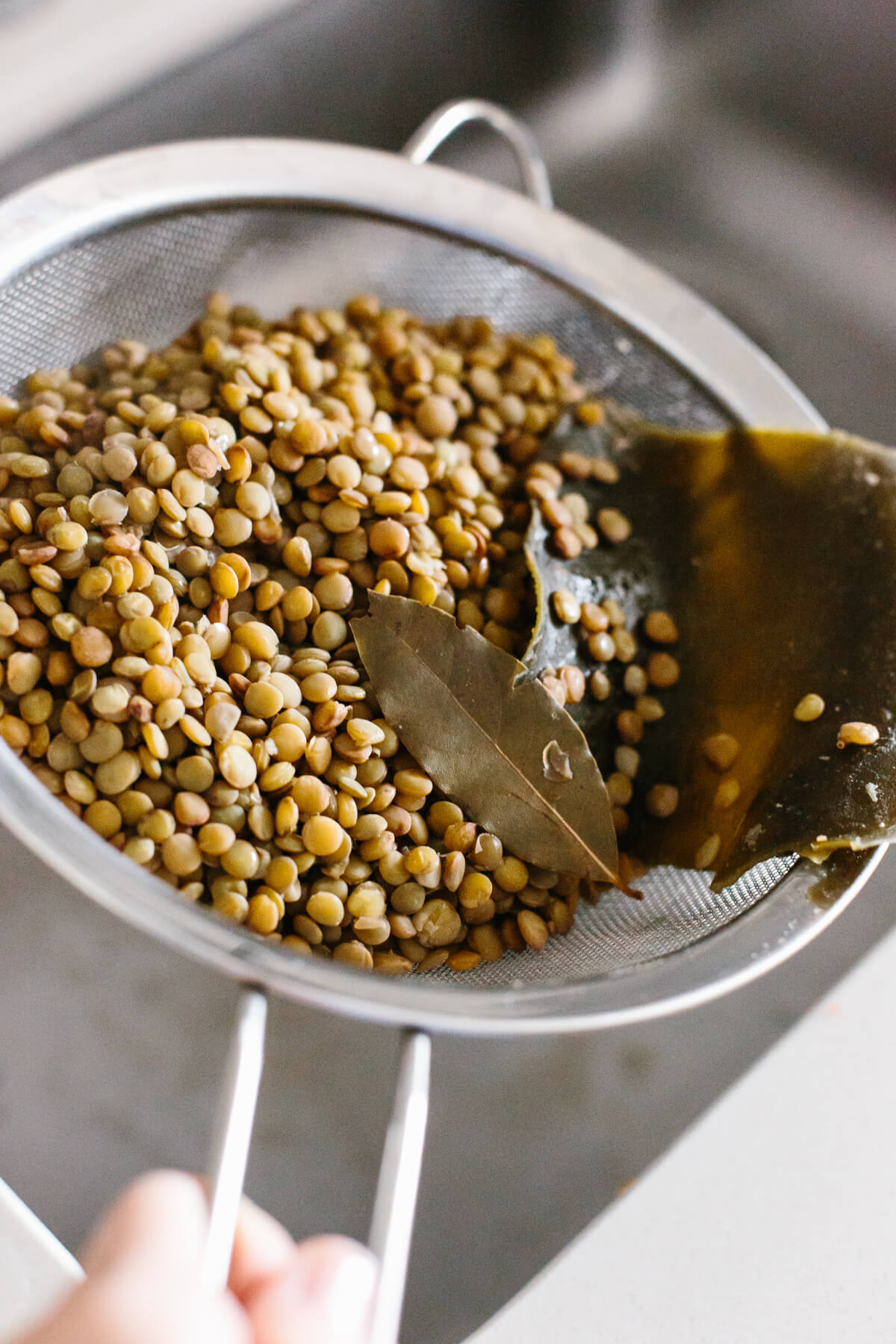 Straining lentils over the sink.