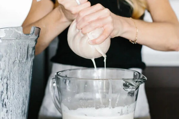 Squeezing almond milk through a nut milk bag