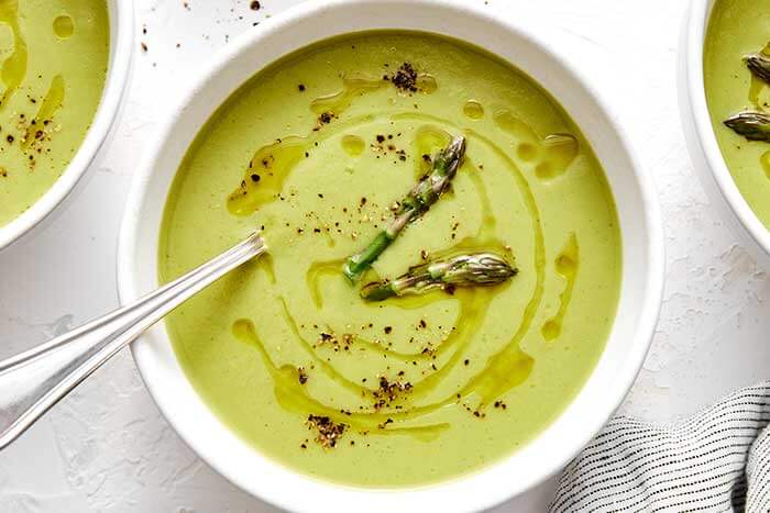 Creamy asparagus soup in a white bowl.