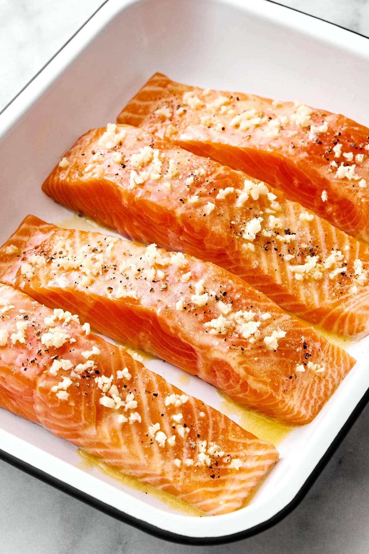 Prepping salmon in a baking tray before baking.