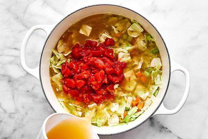 Cooking cabbage soup in a white pot.