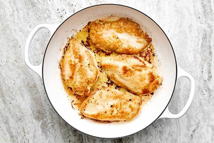 Cooked chicken breasts in a pan.