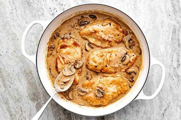 Chicken Marsala in a pan with a spoon.