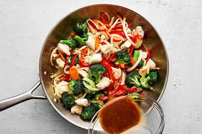 Cooking chicken stir-fry in a pan.
