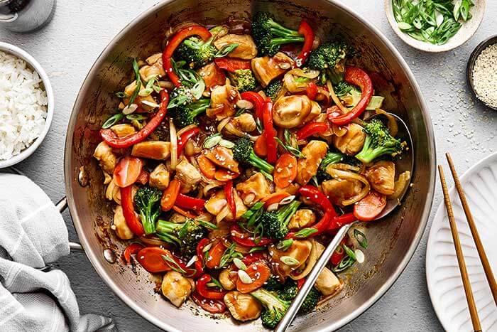 Chicken stir-fry in stainless steel pan.
