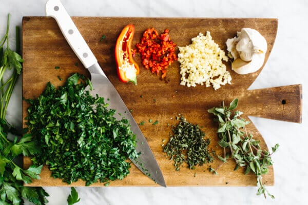 Chopped chimichurri sauce ingredients on a board