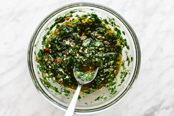 A small bowl of chimichurri sauce with a spoon