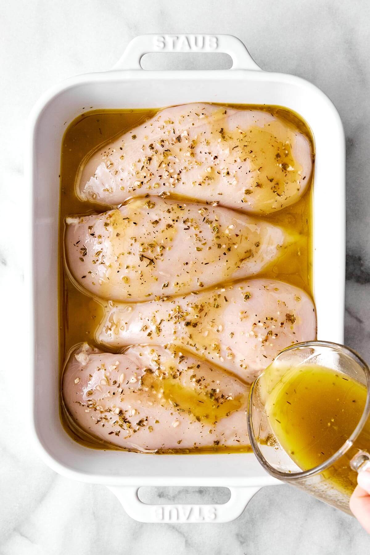 Marinating chicken breasts in a casserole dish.