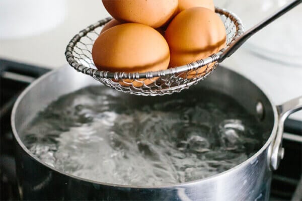 Adding eggs into boiling water for hard boiled eggs