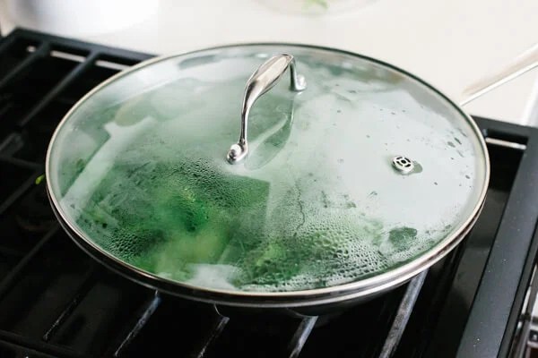 Covering a pan of garlic sauteed spinach for steaming.