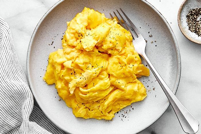 Scrambled eggs on a plate with black pepper.