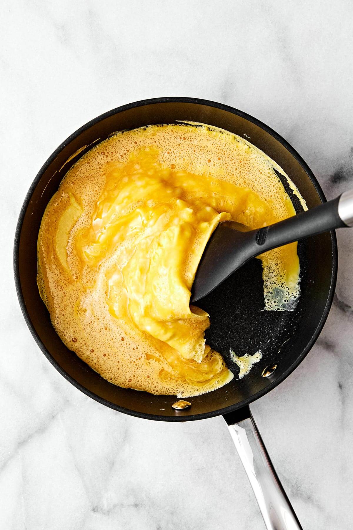 Folding scrambled eggs in a pan.