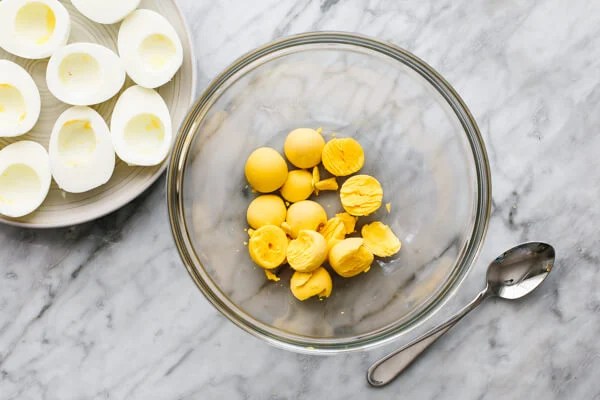 Scooping egg yolks out for smoked salmon deviled eggs