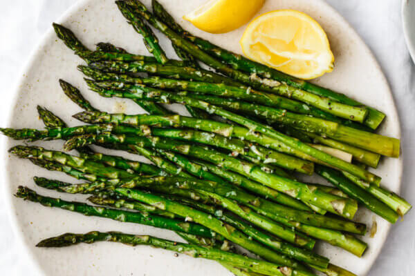 Roasted asparagus on a plate with lemon wedges