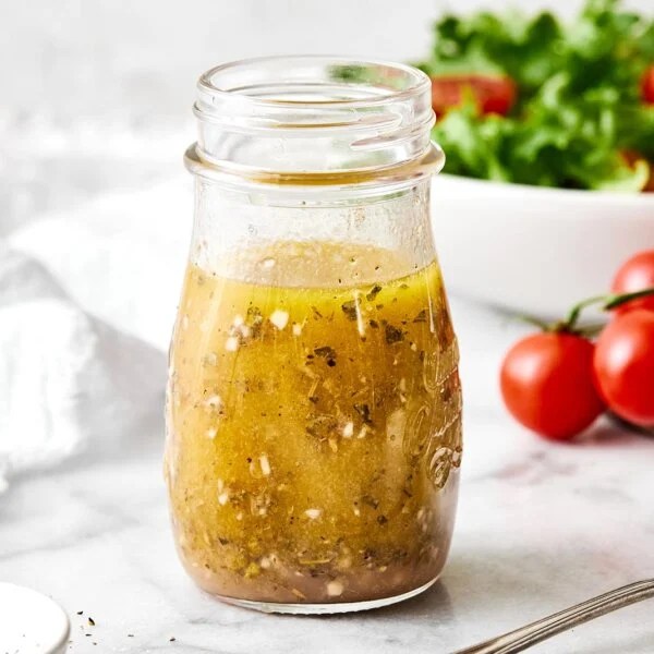 A glass jar of Italian dressing.
