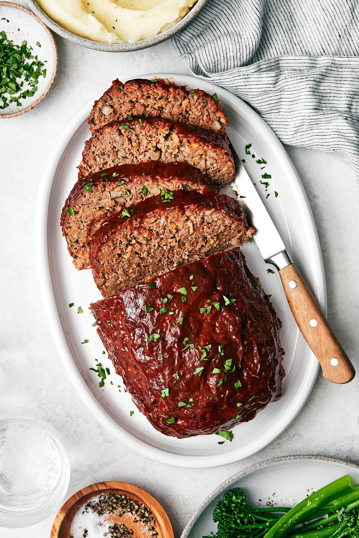 Here's my secret to the best classic meatloaf recipe! It's tender and moist, layered with flavor, and brushed with a tasty meatloaf sauce! A white plate of meatloaf.
