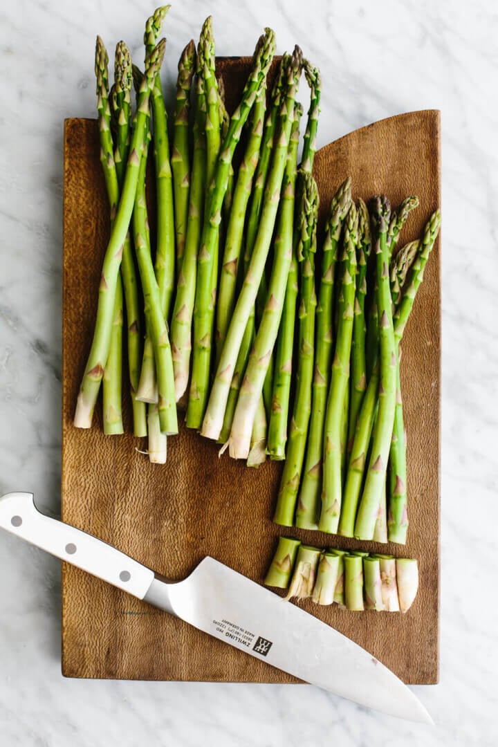Chopping asparagus on a board for roasted asparagus