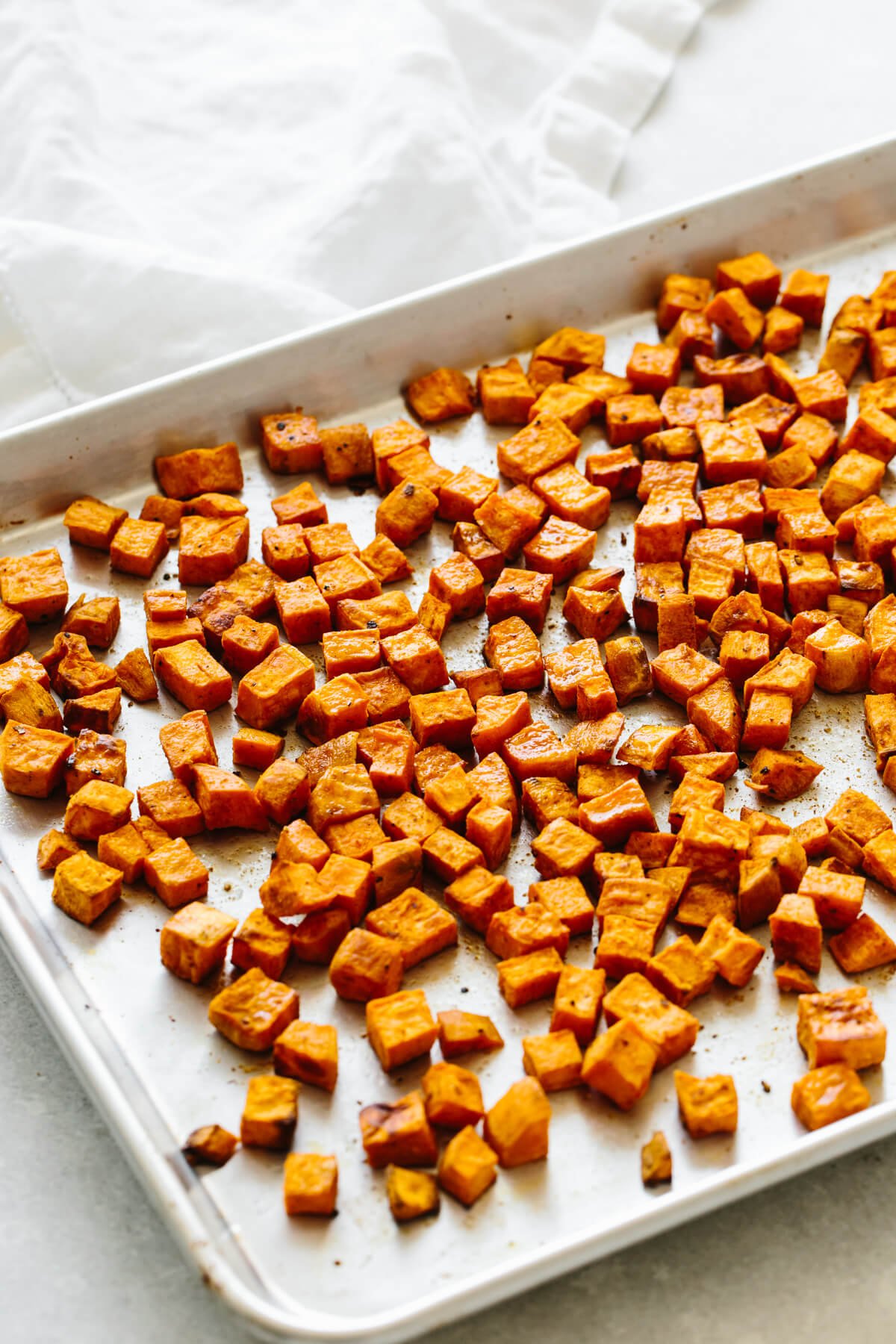Diced and roasted sweet potato on a sheet pan.