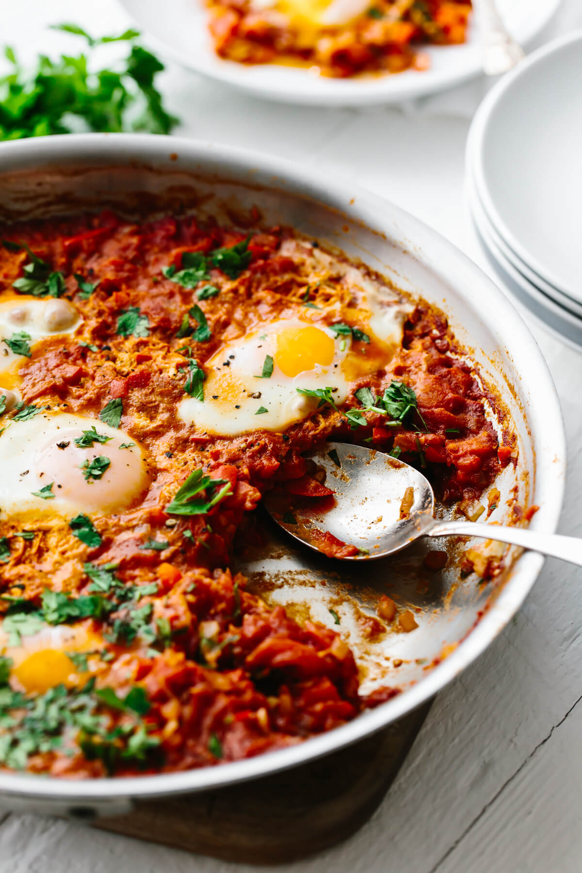 Taking a portion of shakshuka out of the pan.