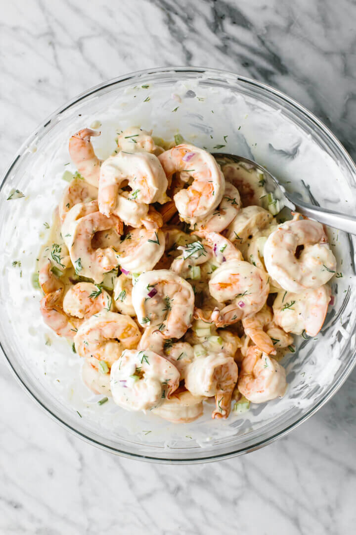 Mixing shrimp salad in a glass bowl