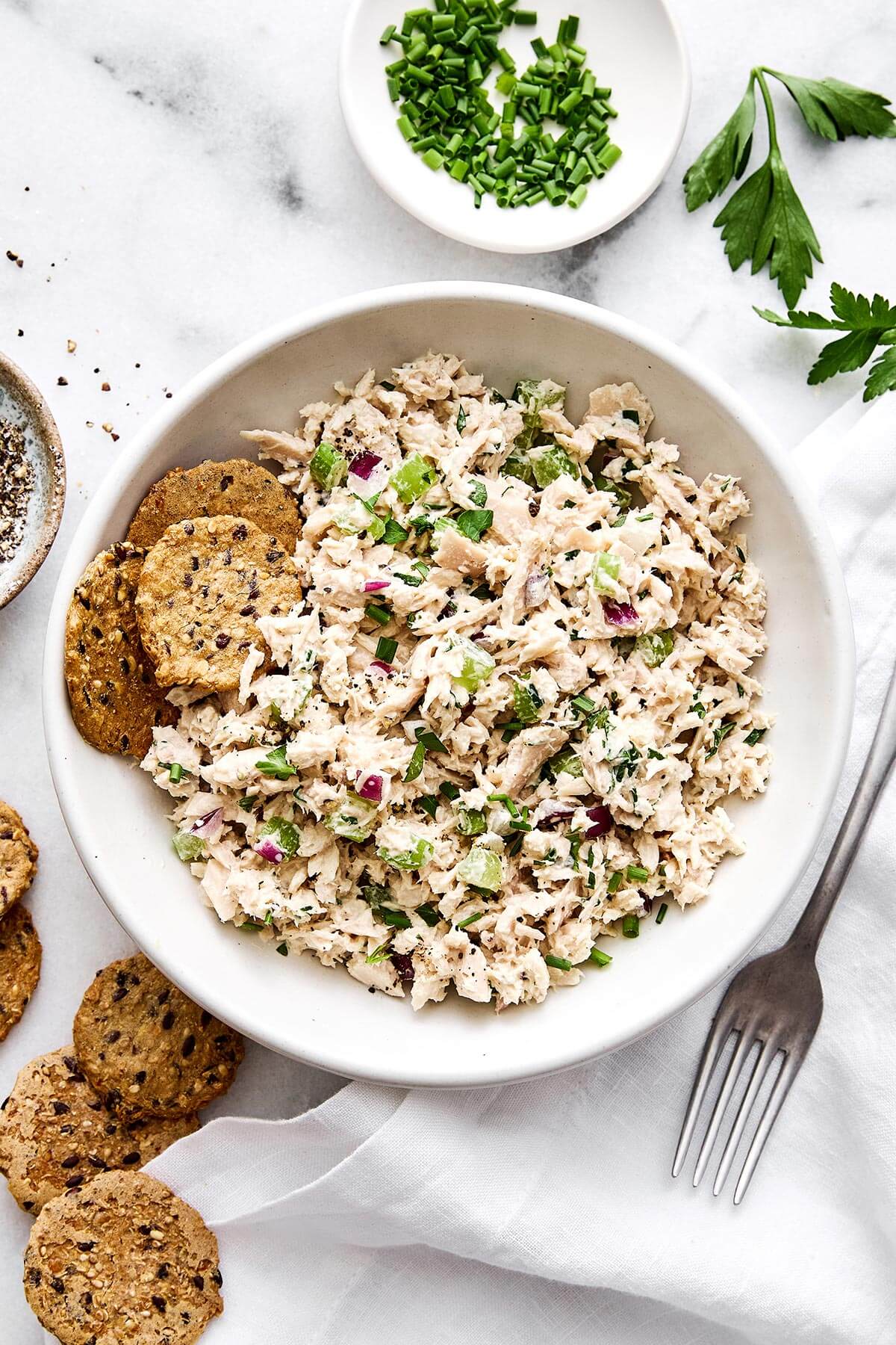 A bowl of tuna salad with crackers.
