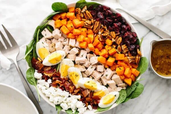 A large bowl with turkey cobb salad next to a vinaigrette bowl.