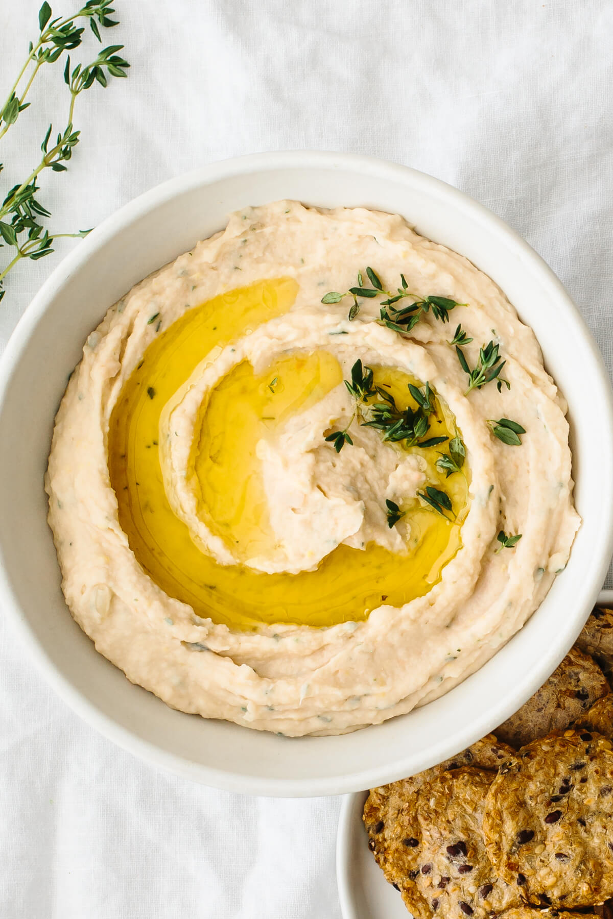 White bean dip in a bowl next to crackers.